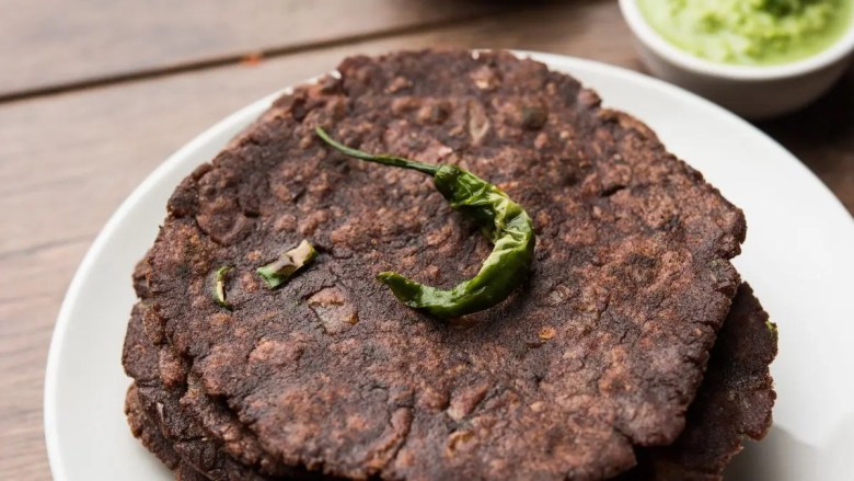 तळलेल्या हिरव्या मिरचीने सुशोभित केलेले नाचनी (रागी) रोटिसची एक प्लेट एकमेकांच्या वरच्या बाजूस रचली गेली, एका लहान वाडग्यात हिरव्या चटणीने सर्व्ह केली.