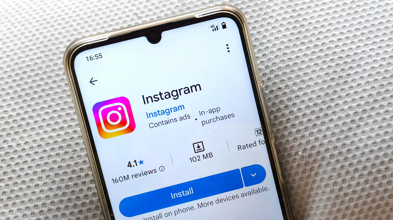 आधुनिक पांढऱ्या पार्श्वभूमी शैलीसह Google Play Store वर Instagram ॲप पृष्ठ दर्शविणारा क्लोज-अप स्मार्टफोन.