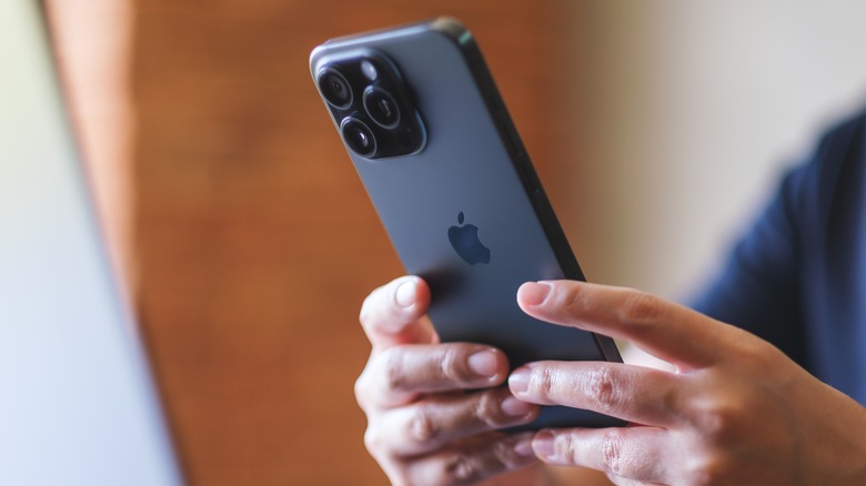 आयफोन धारण केलेली व्यक्ती.