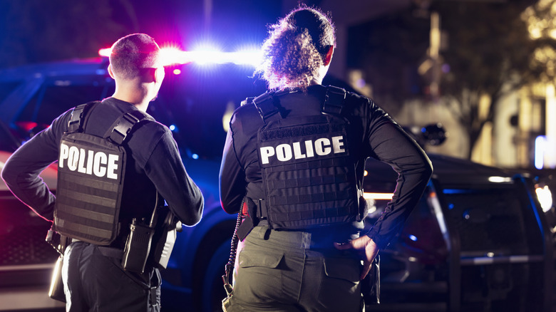 पोलिस अधिकारी त्यांच्या क्रूझरसमोर गुन्हेगारीच्या ठिकाणी