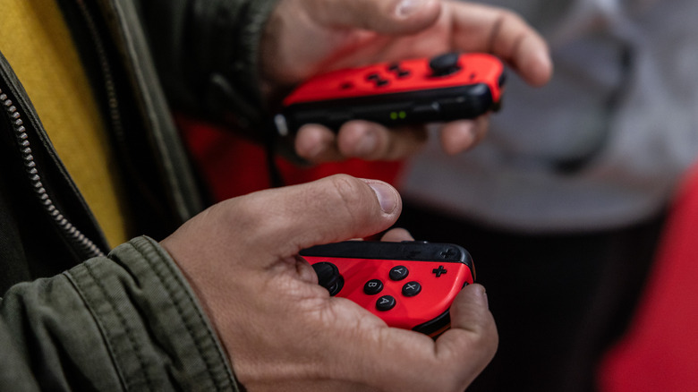 दोन Nintendo Switch Joy-cons धारण केलेली व्यक्ती.