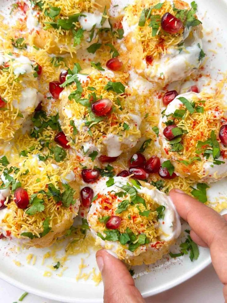 यात हे असू शकते: चीजमध्ये झाकलेली आणि डाळिंबांनी सजलेली अंडी असलेली पांढरी प्लेट