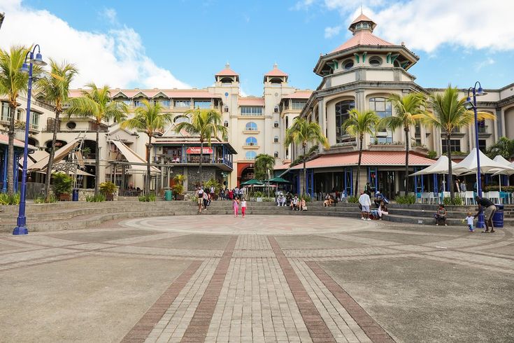 यात याचा समावेश असू शकतो: काही इमारतींसमोरून लोक फिरत आहेत