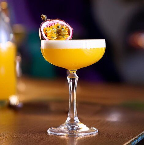 यात हे असू शकते: लाकडी टेबलाच्या वर एक नारिंगी पेयाने भरलेला ग्लास