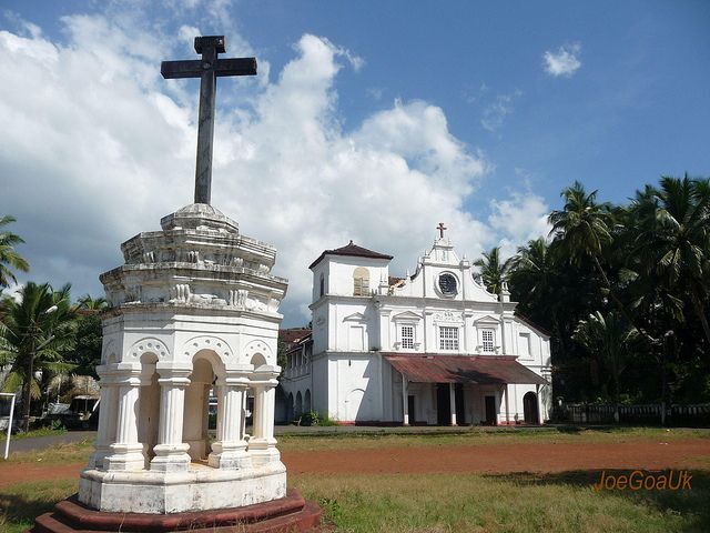 यात हे असू शकते: वर क्रॉस असलेली मोठी पांढरी इमारत आणि मागील जमिनीवर पामची झाडे