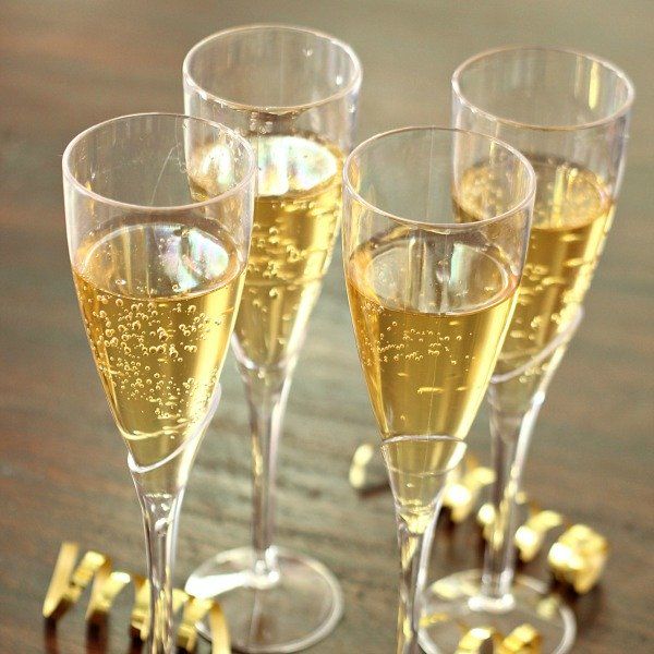 यात हे समाविष्ट असू शकते: कॉन्फेटीच्या शेजारी लाकडी टेबलावर शॅम्पेनने भरलेले चार ग्लास