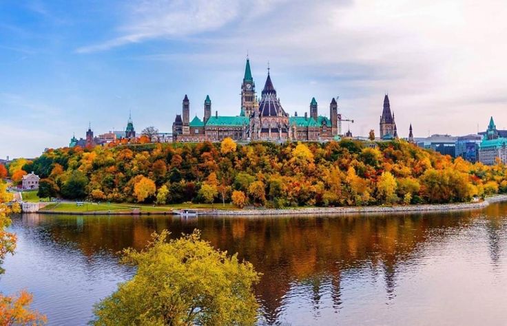 यात हे असू शकते: पाण्याच्या शेजारी हिरव्यागार टेकडीवर बसलेला एक मोठा वाडा