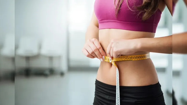 इंच टेपने तिची कंबर मोजणारी स्त्री