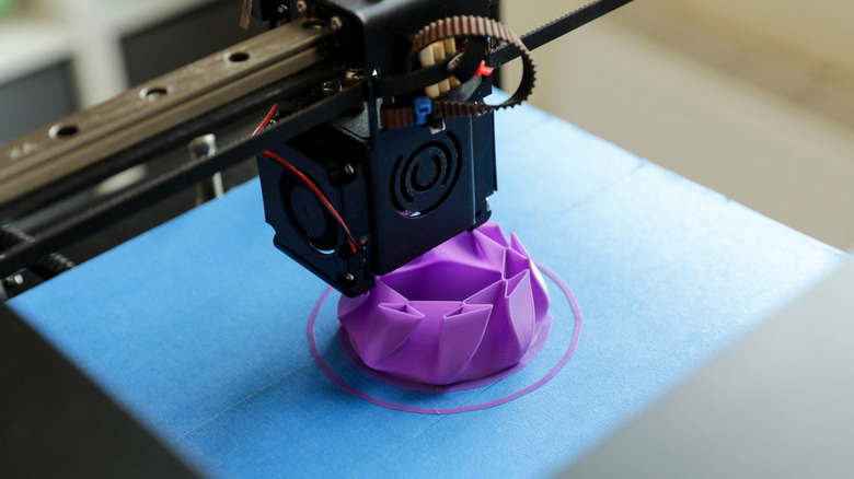 जांभळ्या रंगाची वस्तू तयार करणारा 3D प्रिंटर.