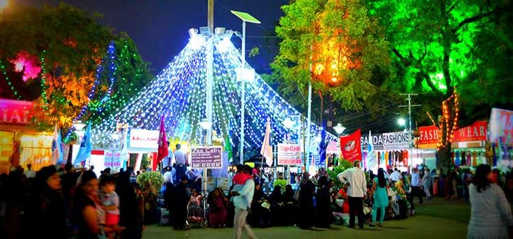 यात हे समाविष्ट असू शकते: दिव्याने झाकलेल्या तंबूभोवती लोकांचा जमाव उभा आहे