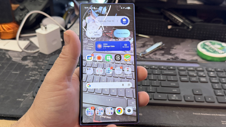 पारदर्शक वॉलपेपरसह Android फोन धरलेला माणूस