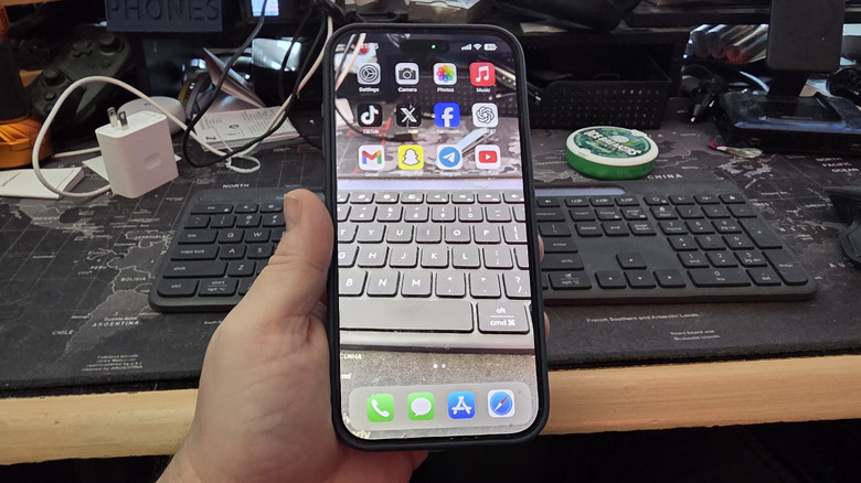 पारदर्शक वॉलपेपरसह आयफोन धरलेला एक माणूस