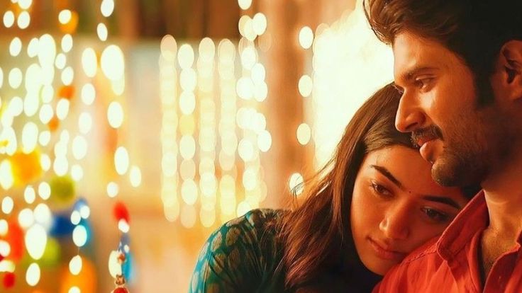 यात हे असू शकते: एक स्त्री आणि पुरुष काही ख्रिसमसच्या दिव्यांसमोर सेल फोनकडे पाहत आहेत