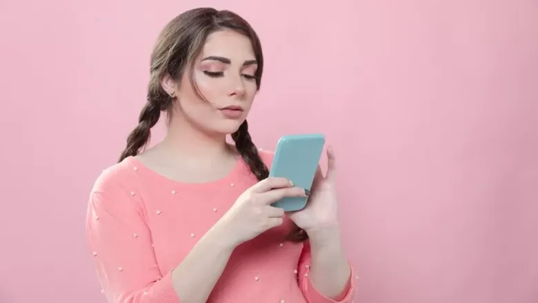 स्त्री तिच्या मोबाईलकडे पाहत आहे