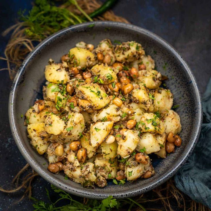 यात हे असू शकते: काही अजमोदा (ओवा) शेजारी निळ्या कापडाच्या वर बटाटे आणि नटांनी भरलेला एक वाडगा