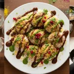 वर चिंचेची गोड चटणी, हिरवी चटणी, चाट मसाला आणि लाल तिखट, नंतर सर्व्ह करण्यापूर्वी शेव, डाळिंबाचे दाणे आणि ताजी कोथिंबीर घालून सजवा.