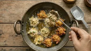 मिश्रणाचे छोटे भाग हाताने किंवा चमच्याने गरम तेलात टाका आणि मध्यम आचेवर सोनेरी तपकिरी आणि कुरकुरीत होईपर्यंत तळा.