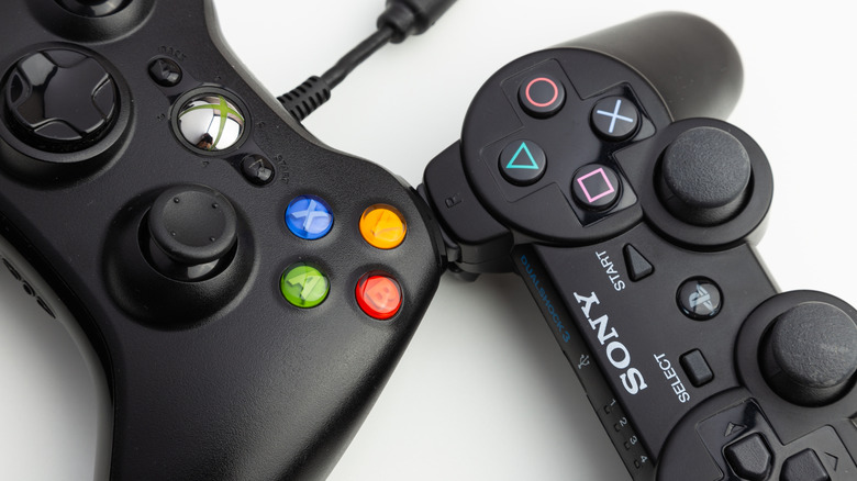 पांढऱ्या पृष्ठभागावर PS3 आणि Xbox 360 कंट्रोलरचा क्लोज-अप.