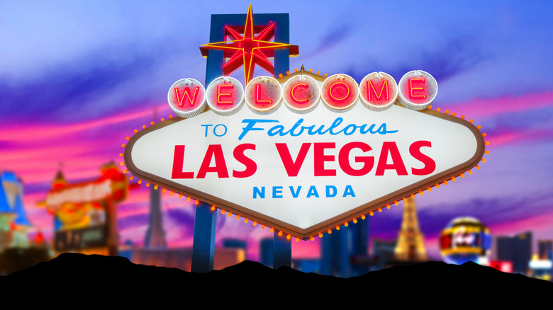 लास वेगासचे चिन्ह संध्याकाळच्या वेळी उजळले आणि त्याच्या मागे पट्टी पेटली