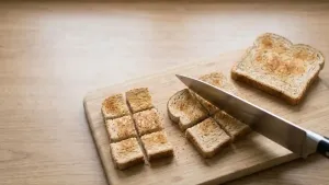 टोस्ट केलेले ब्रेडचे तुकडे चाकूने चार लहान, समान चाव्याच्या आकाराचे तुकडे केले जातात.