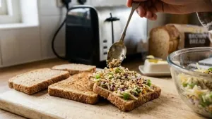 एक चमचा तयार केलेली चीझी भाजी टॉपिंग लहान टोस्ट केलेल्या ब्रेडच्या तुकड्यांवर समान रीतीने पसरवा.