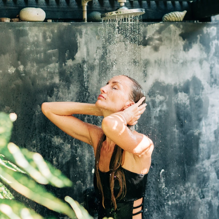 बाहेरचा शॉवर वापरणारी सोनेरी स्त्री