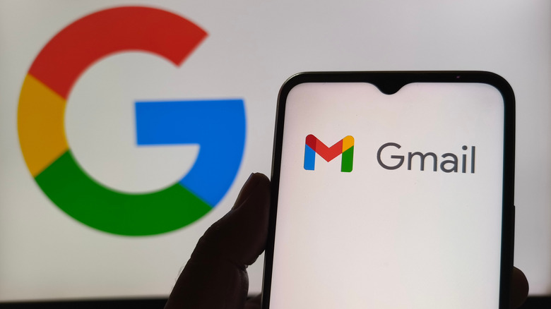पार्श्वभूमीत Google लोगोच्या विरुद्ध फोनवर Gmail लोगो