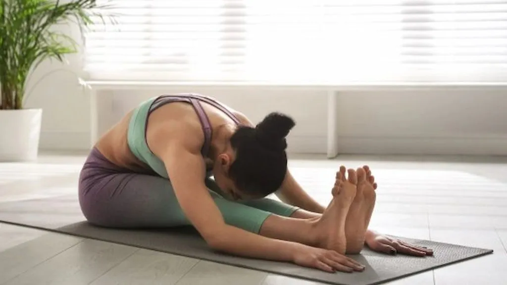 महिला बसलेली फॉरवर्ड बेंड योगा करताना