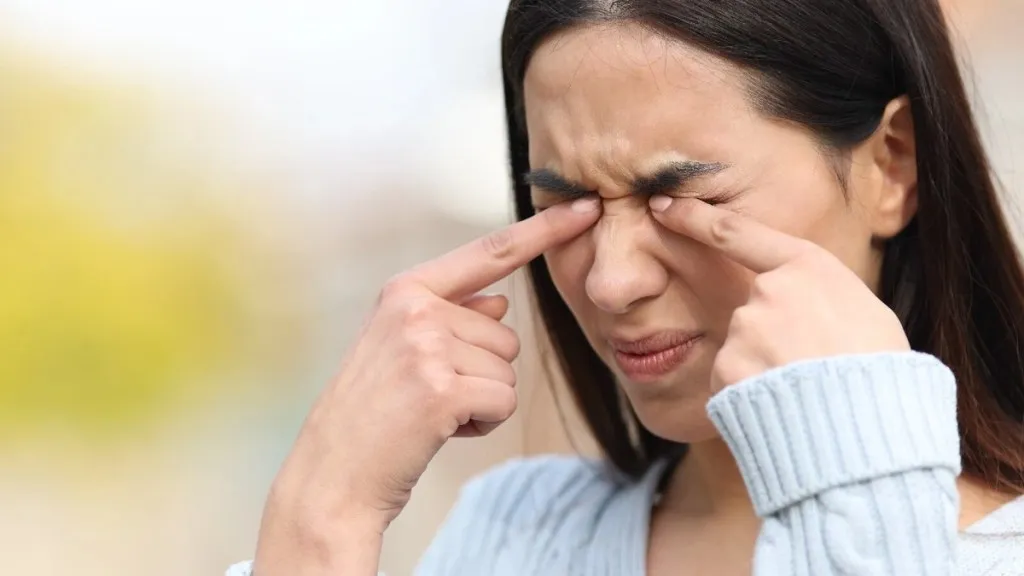 स्त्री तिच्या डोळ्यांवर बोट ठेवते