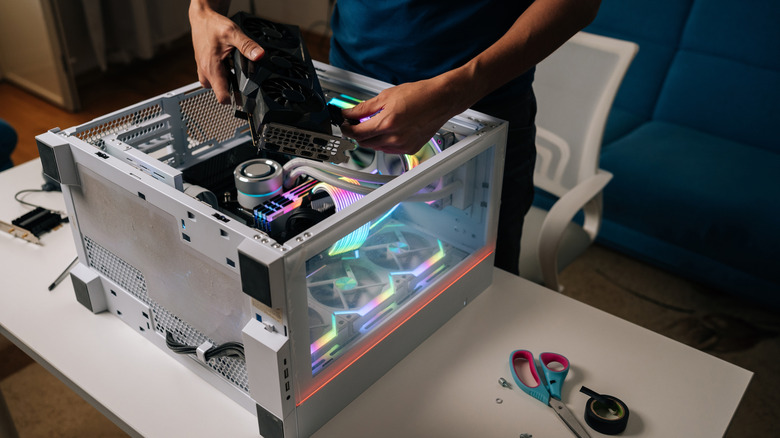 एक तंत्रज्ञ डेस्कटॉप पीसीमध्ये ग्राफिक्स कार्ड स्थापित करतो