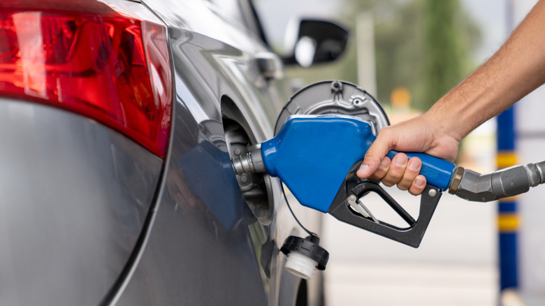 गॅस स्टेशनवर कारमध्ये गॅस पंप करणाऱ्या व्यक्तीचा क्लोज शॉट