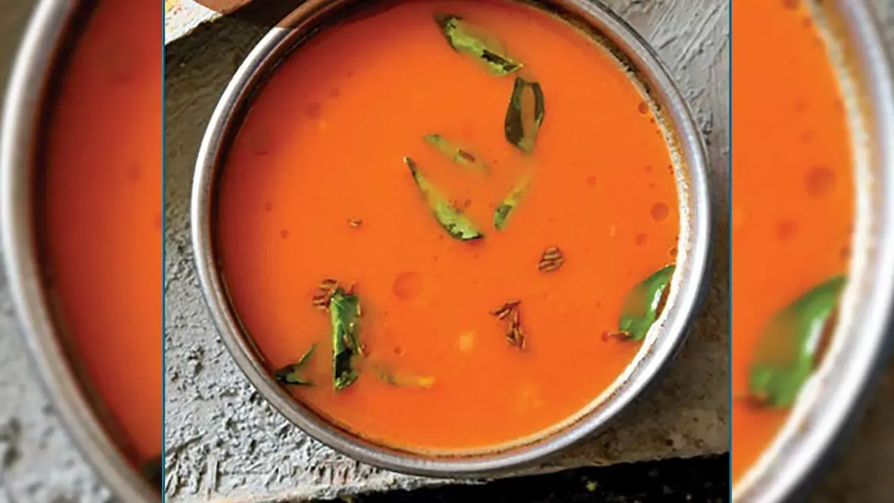 ताज्या कढीपत्त्यांनी गुळगुळीत केशरी चटणी टोमॅटोने भरलेल्या लहान स्टीलच्या वाडग्याचे वरपासून खालचे दृश्य