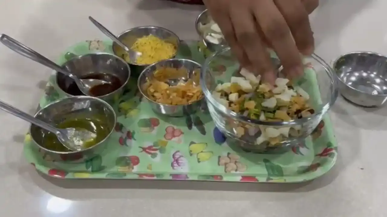 वेगवेगळ्या चवदार भारतीय चटण्या आणि मसाल्यांसह मधुर काळ्या चण्या काला चना चाट तयार करताना हाताने बंद करा.