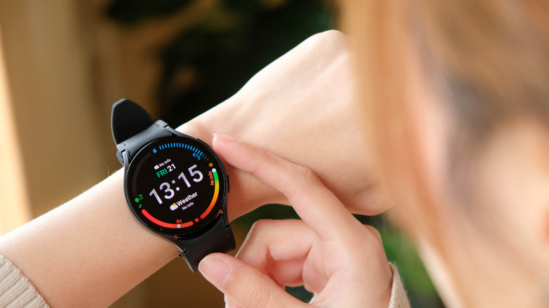 Galaxy Watch ला स्पर्श करणारी व्यक्ती
