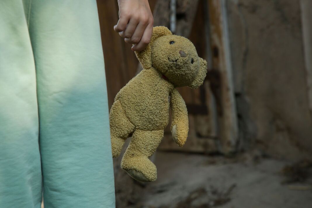एका लहान मुलाच्या हातात जुना, प्लश टेडी बेअर आहे एका लहान मुलाच्या हातात जुना, प्लश टेडी बेअर आहे