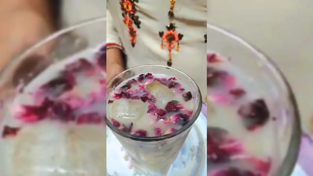 पारंपारिक एम्ब्रॉयडरी कुर्ता परिधान केलेल्या व्यक्तीने ग्लासमध्ये तरंगणाऱ्या बर्फाचे तुकडे असलेले थंडगार गुलाबाच्या पाकळ्याचे दूध पेय.